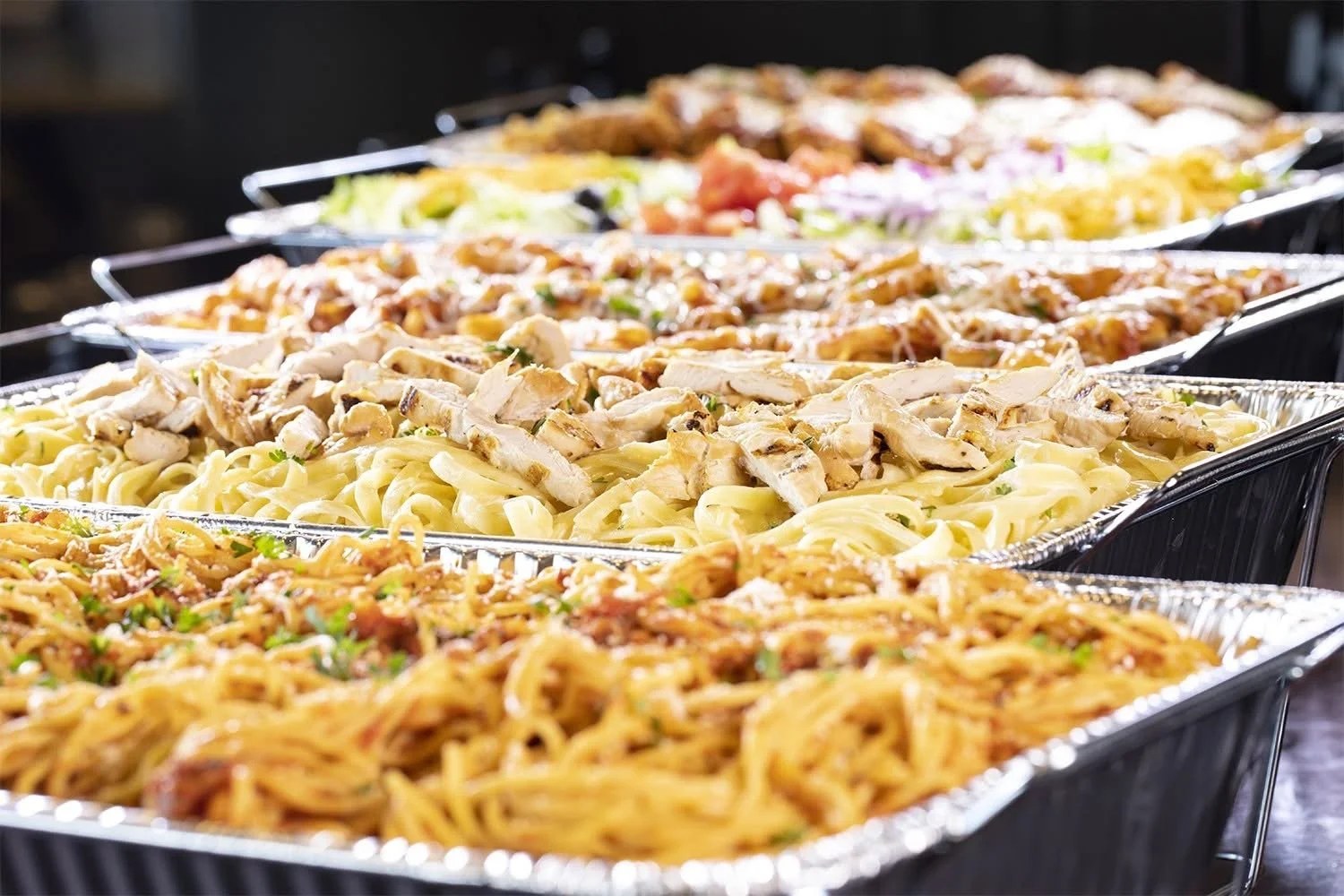 Trays of catering food ready for delivery — pasta and grilled chicken