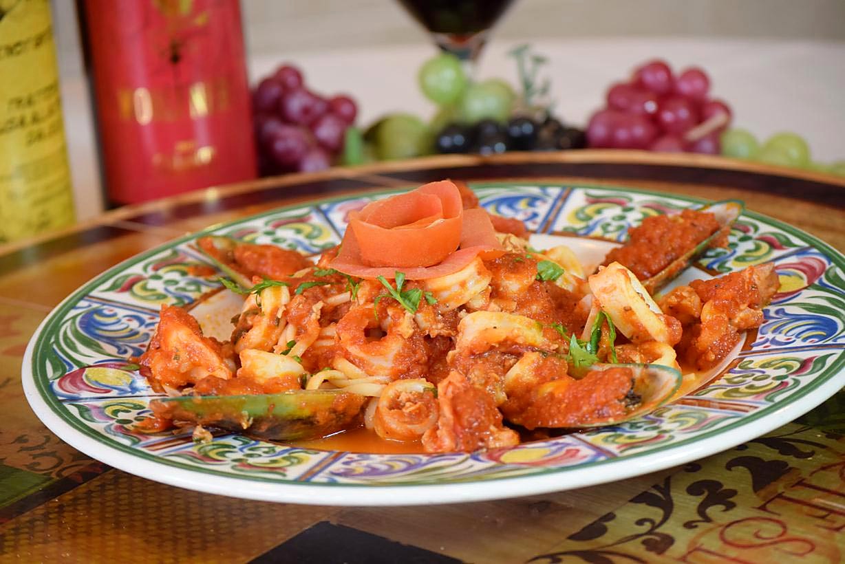 Seafood pasta plated with a tomato rose garnish